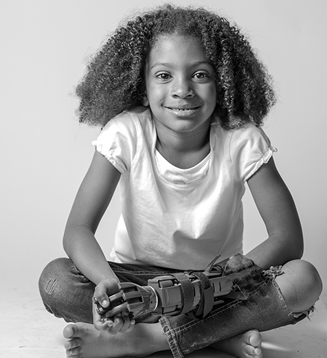 Black and white photo of a young girl sitting cross-legged on a light background