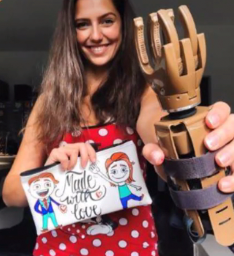 Woman holding an LN-4 prosthetic hand and a sign with cartoon characters and text.