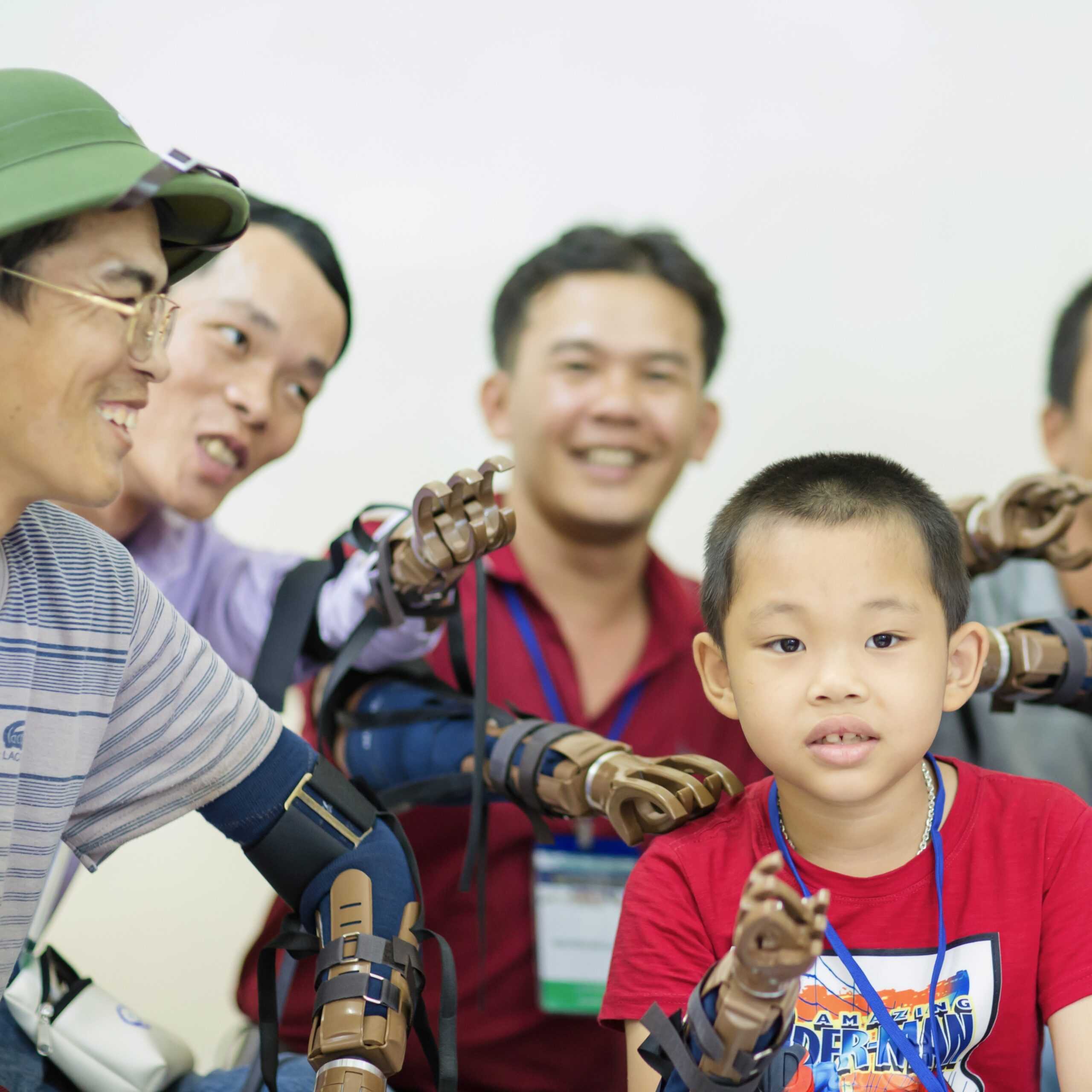 Group of people smiling and wearing prosthetic hands from Build-A-Hand® Team Building Kit activity