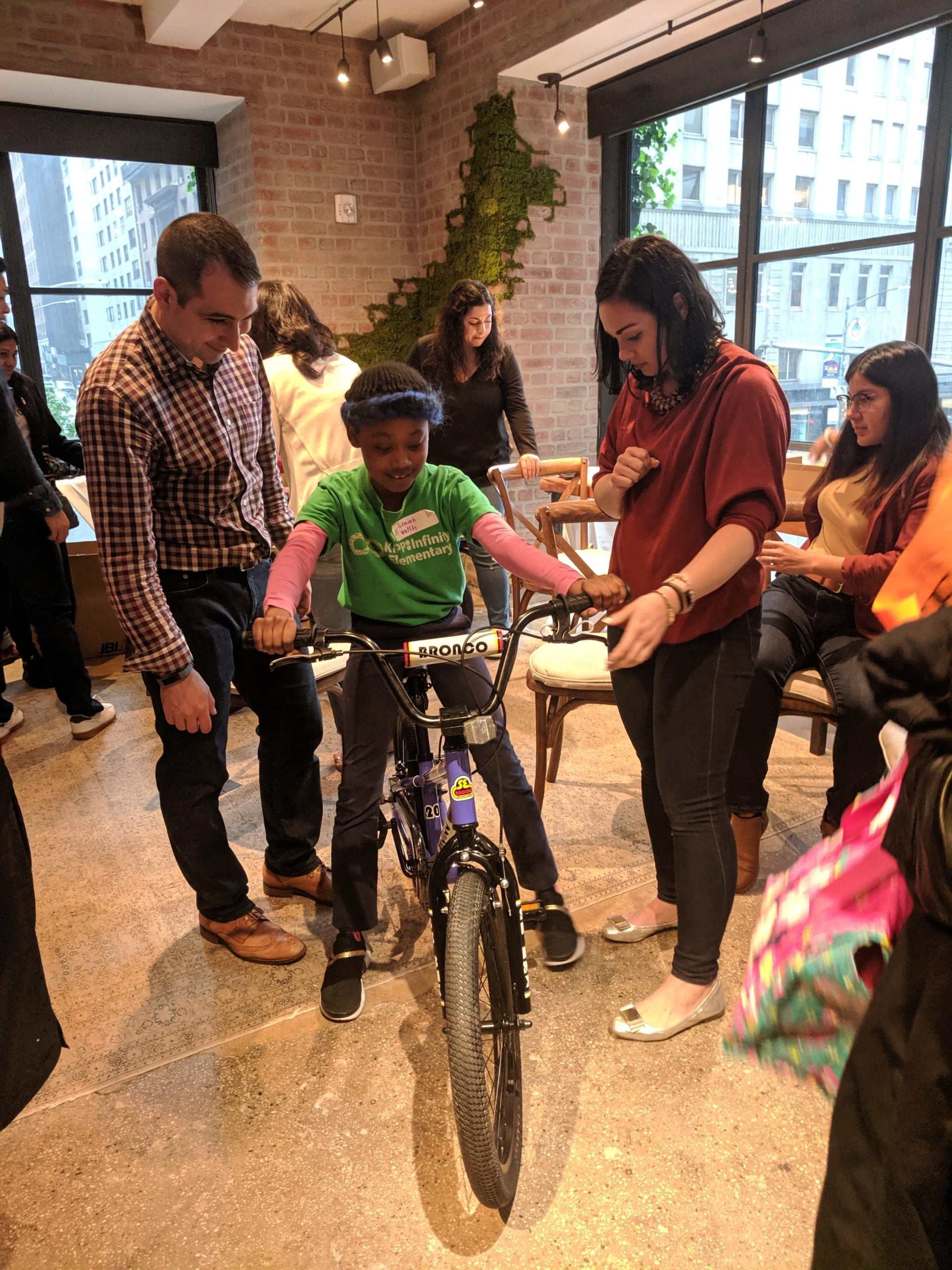 Team building event with child assembling Life Cycles™ BMX bike and group support indoors