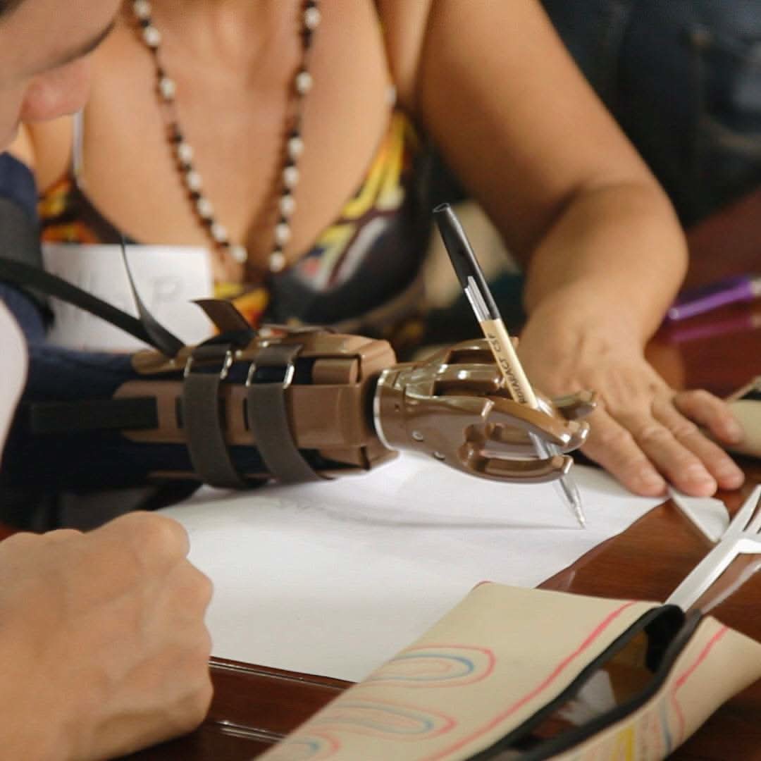 Build-A-Hand® Team Building Kit with prosthetic hand writing with a pen during group activity
