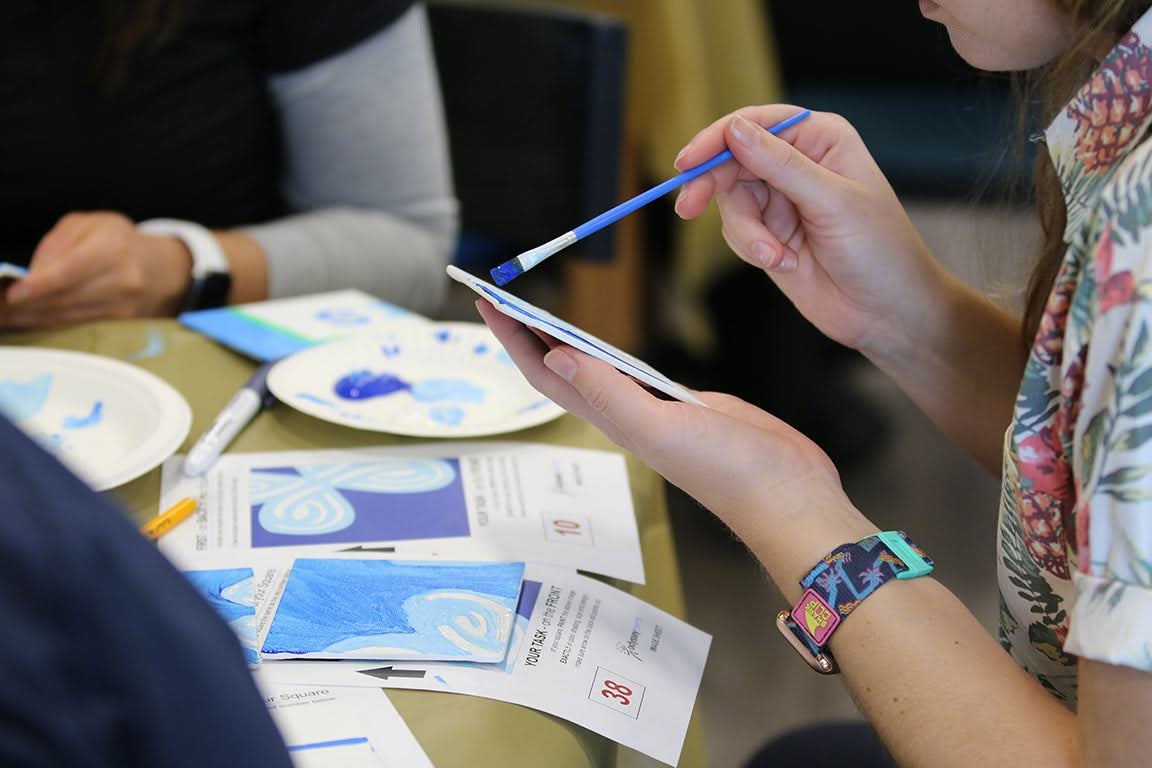 Person painting a mosaic tile using the Team Mosaic™ Kit for creative team-building activity