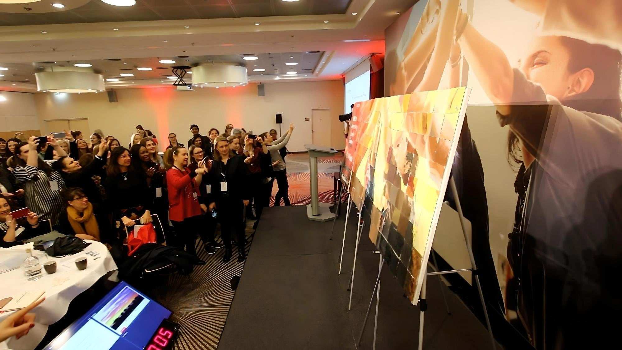 Corporate team building event showcasing the Team Mosaic™ Kit collaborative art project with participants capturing the moment.