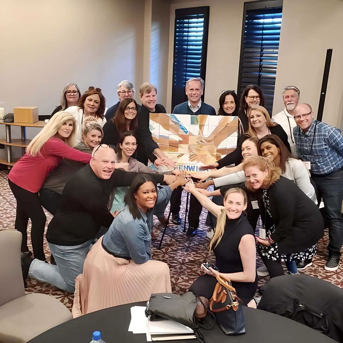 Group of coworkers displaying completed Team Mosaic™ Kit artwork for team building and collaboration activity