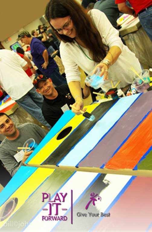 Team building activity with Play-it-Forward™ Kit assembling and painting cornhole boards together