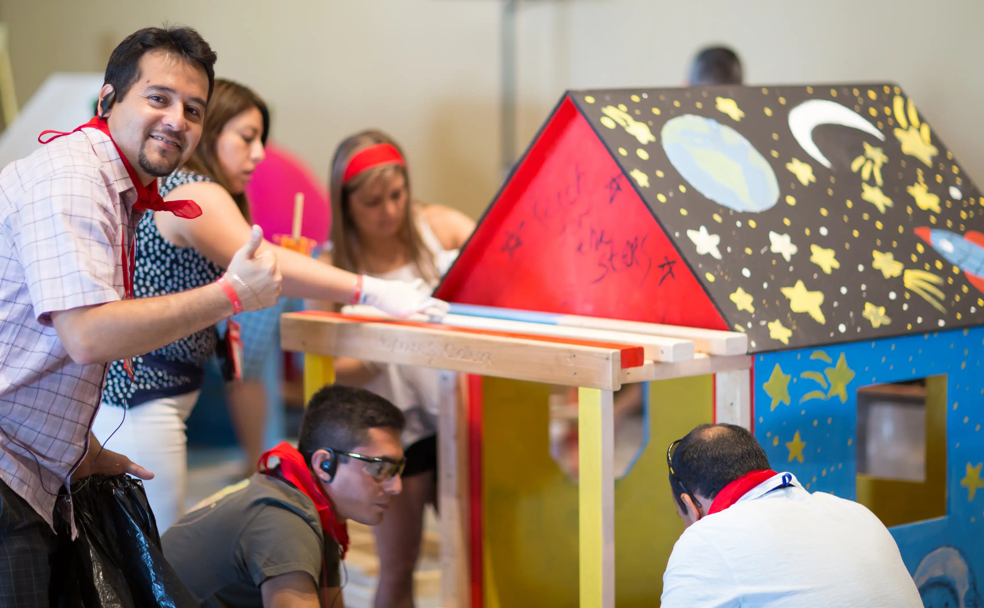 Group of people working on a colorful cardboard house model