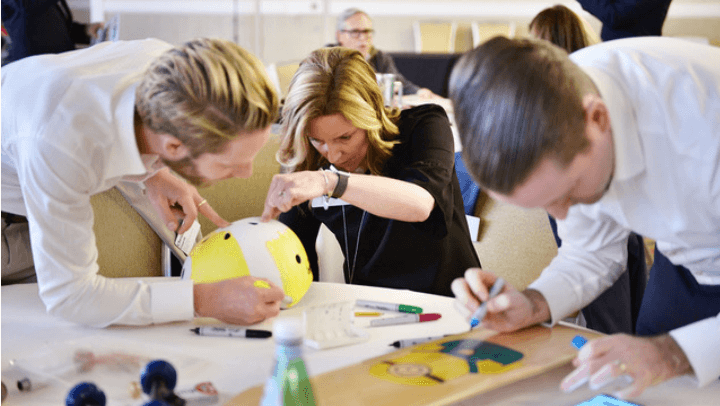 Team members using The Board Meeting™ Kit to creatively decorate helmet and skateboard for team building activity