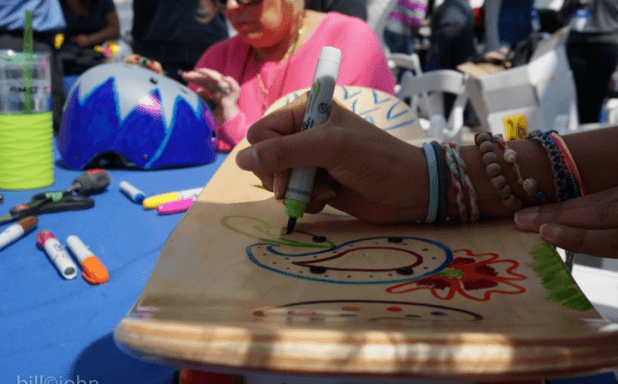 Person decorating a skateboard deck with colorful markers using The Board Meeting™ Kit for team building activities