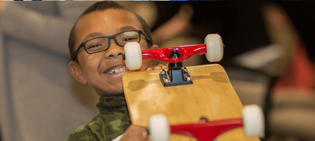 Smiling boy holding a skateboard from The Board Meeting™ Kit team building activity