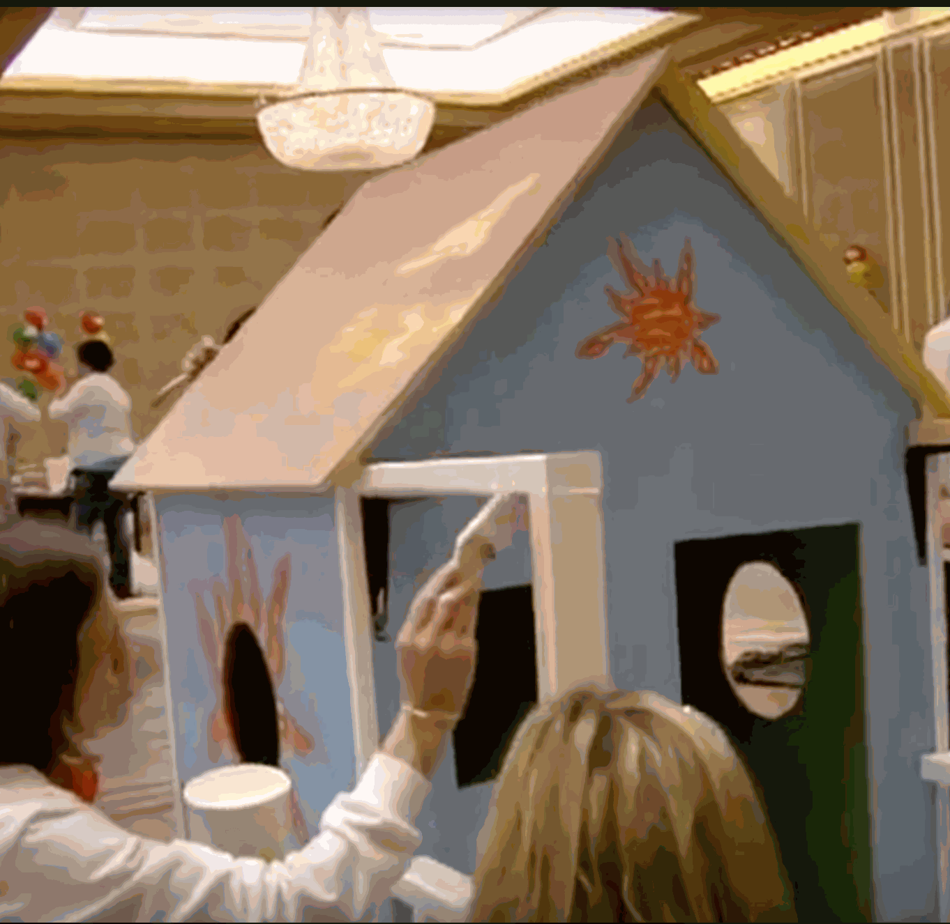 Team building with Playhouse Challenge™ Kit showing people painting a colorful wooden playhouse indoors