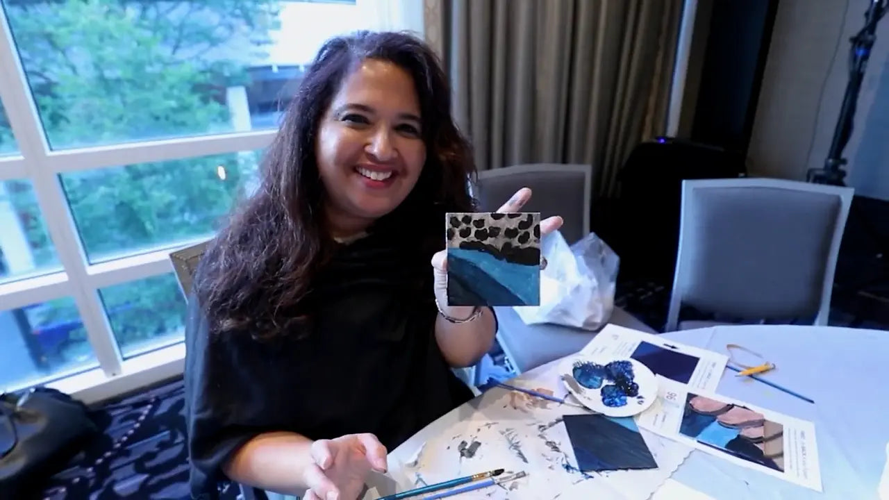Woman holding a Team Mosaic tile with leopard print pattern in a room with a window and chairs.