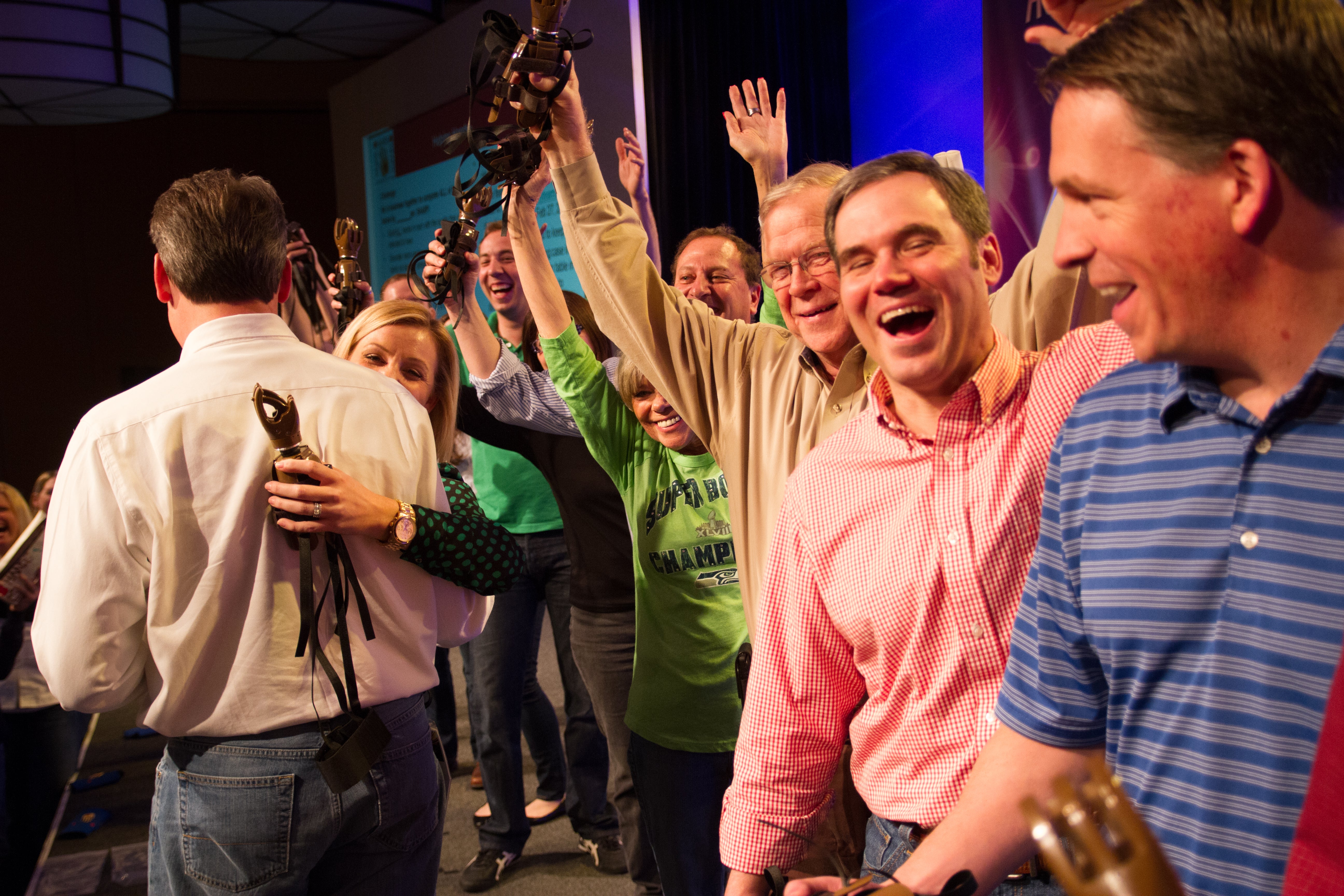 Group of people in a celebratory mood with raised hands, at an Odyssey Teams Build-a-Hand event