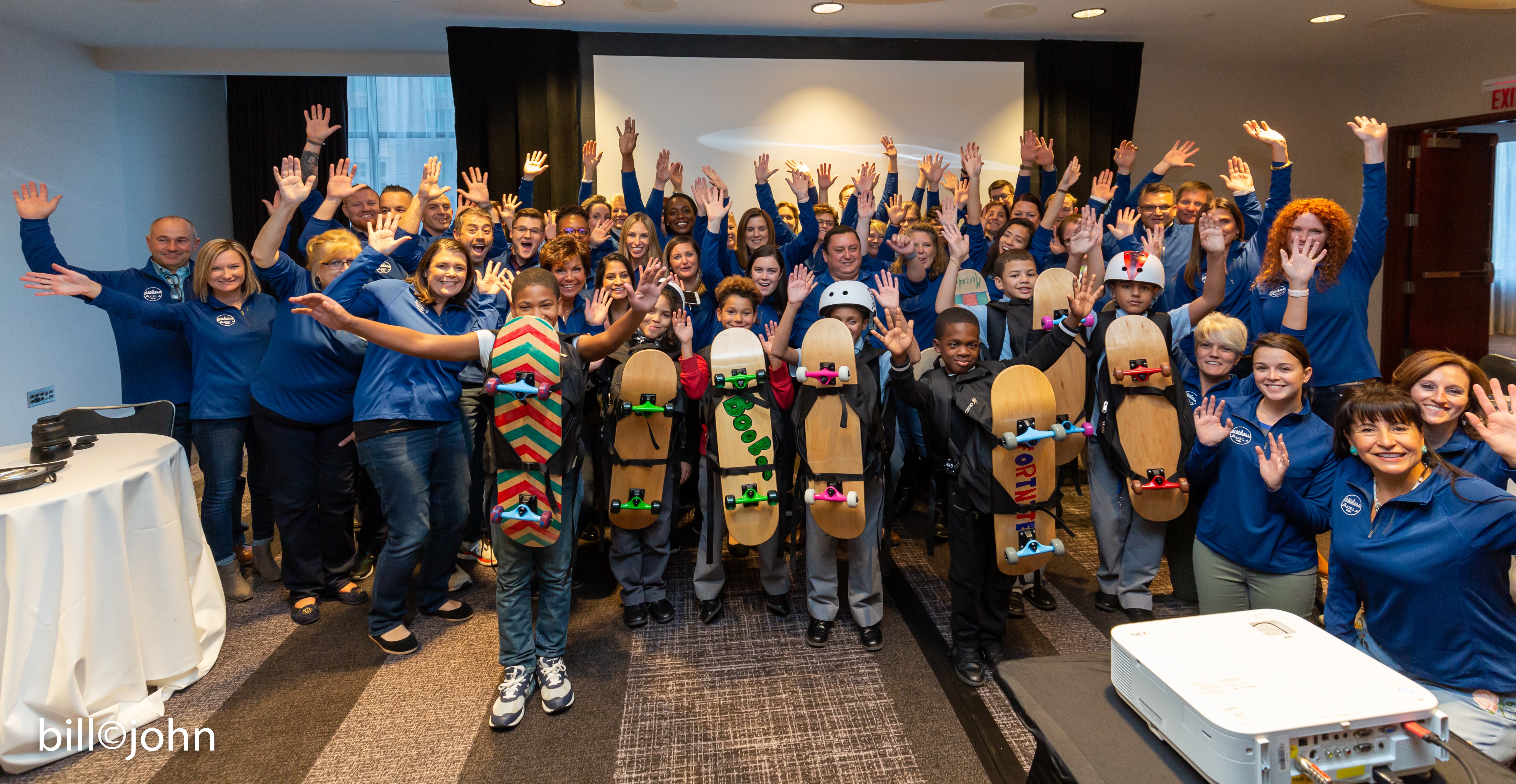 Group of people in a conference room holding skateboards 