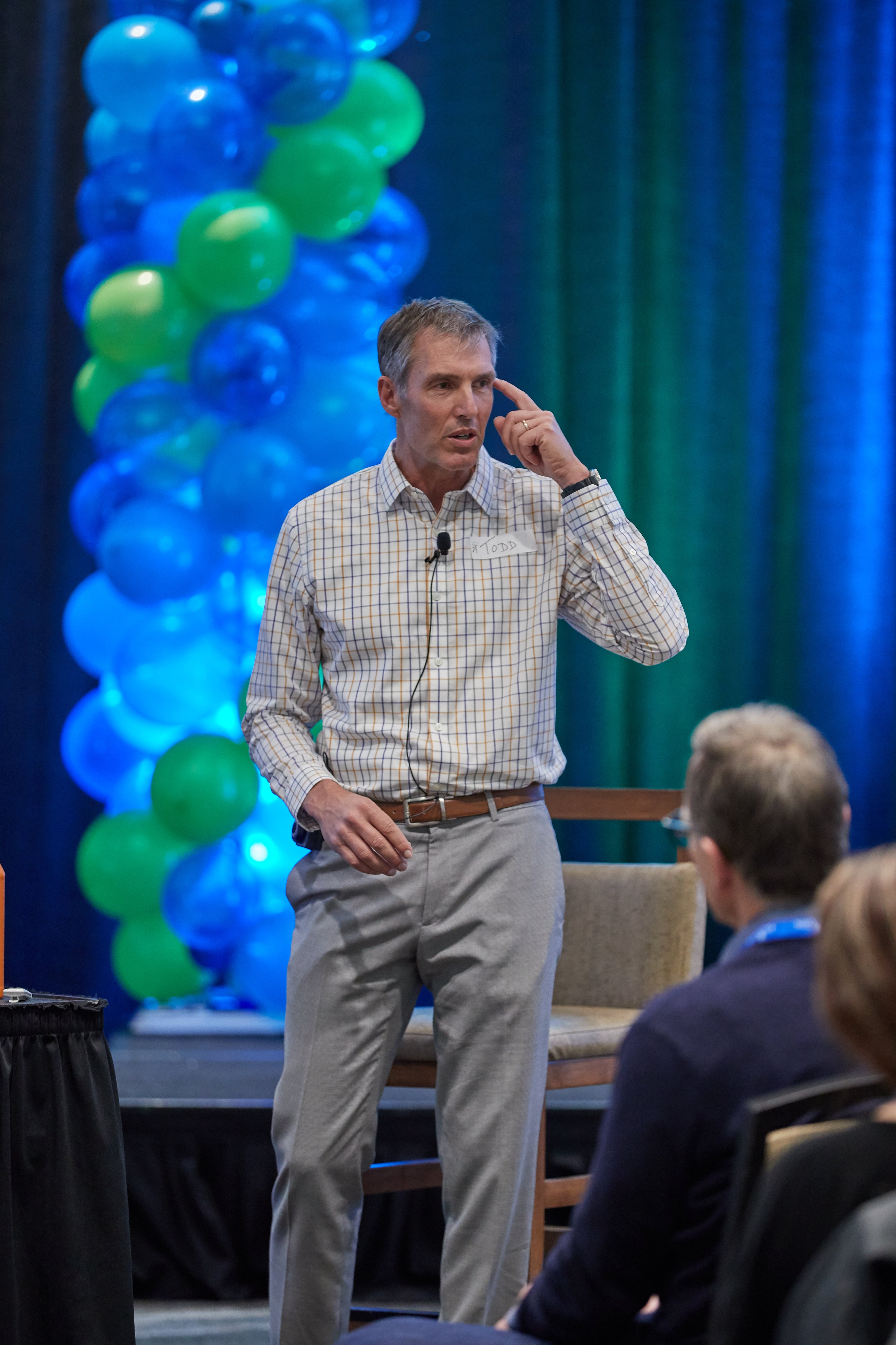Man giving a presentation with balloons and a curtain in the background