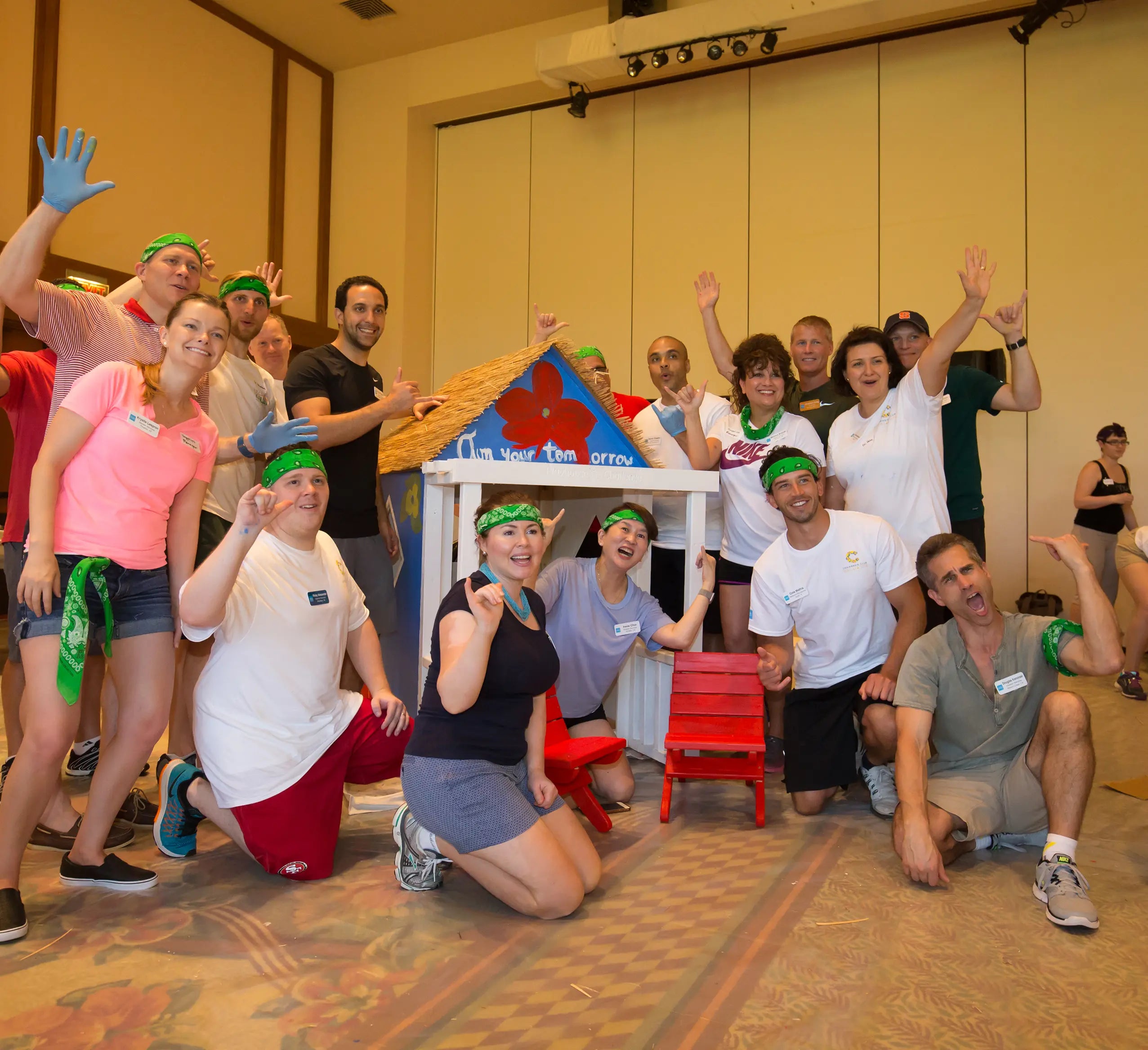 Group of people posing in a room with a small table and chairs.